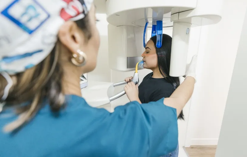 Profesional de la Clínica Dental Moaña realizando una radiografía panorámica a una paciente joven
