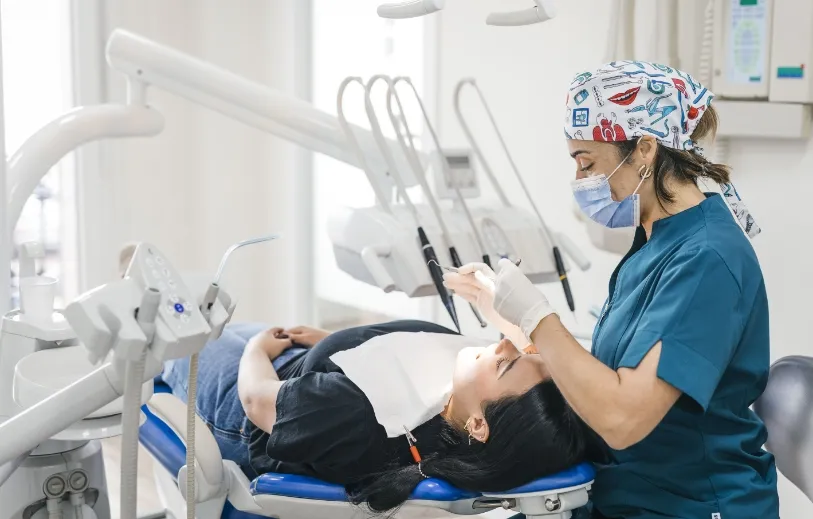 Profesional de la Clínica Dental Moaña atendiendo a una paciente en el sillón dental